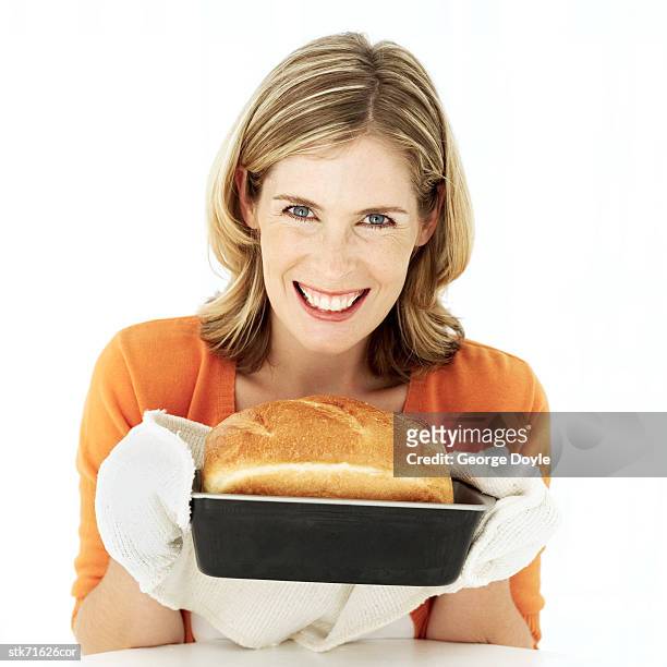 portrait of a young woman holding out a freshly baked loaf of bread - get out stock pictures, royalty-free photos & images