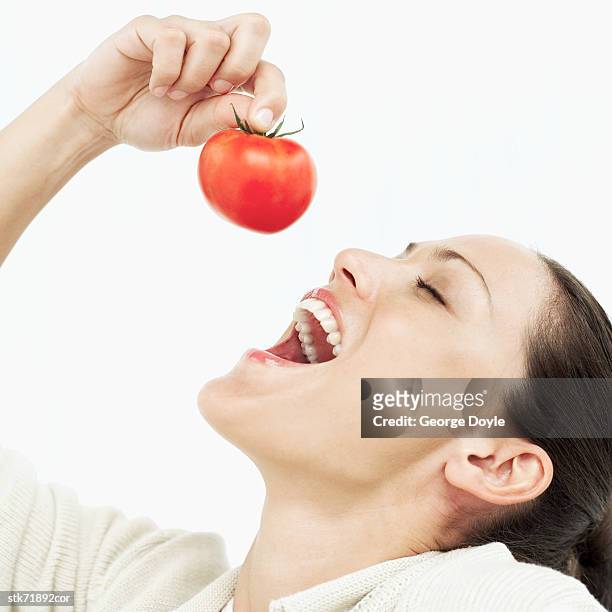 woman holding a tomato over her open mouth - open mouth food ストックフォトと画像