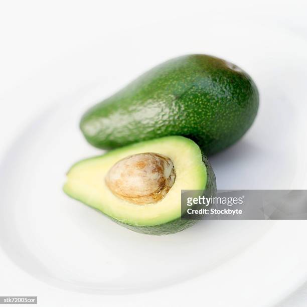close-up of an avocado on a plate - pflanzliches entwicklungsstadium stock-fotos und bilder