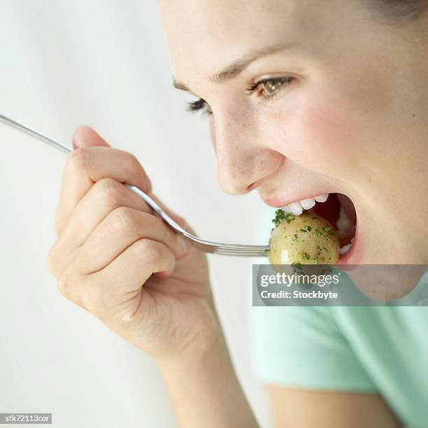 woman eating a potato with a fork - taste of john paul ataker presentation spring 2016 new york fashion week stockfoto's en -beelden