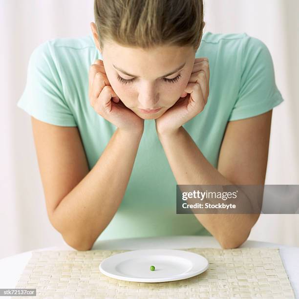 woman looking at a pea on a plate - magnoliopsida bildbanksfoton och bilder