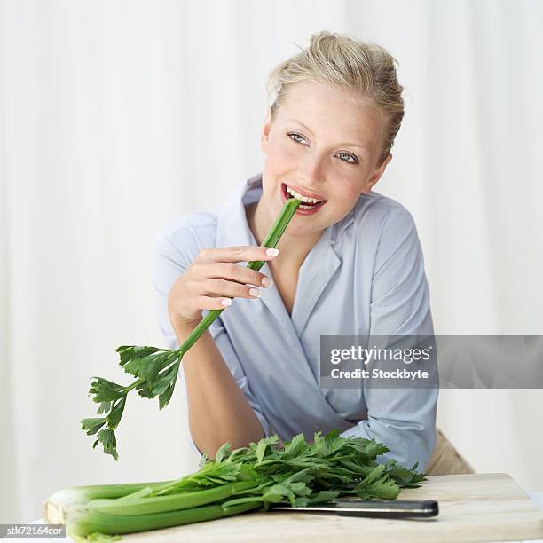 woman biting into a stick of celery - taste of john paul ataker presentation spring 2016 new york fashion week stockfoto's en -beelden