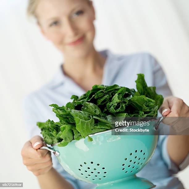 woman holding a colander of washed greens (selective focus) - crucifers stock pictures, royalty-free photos & images