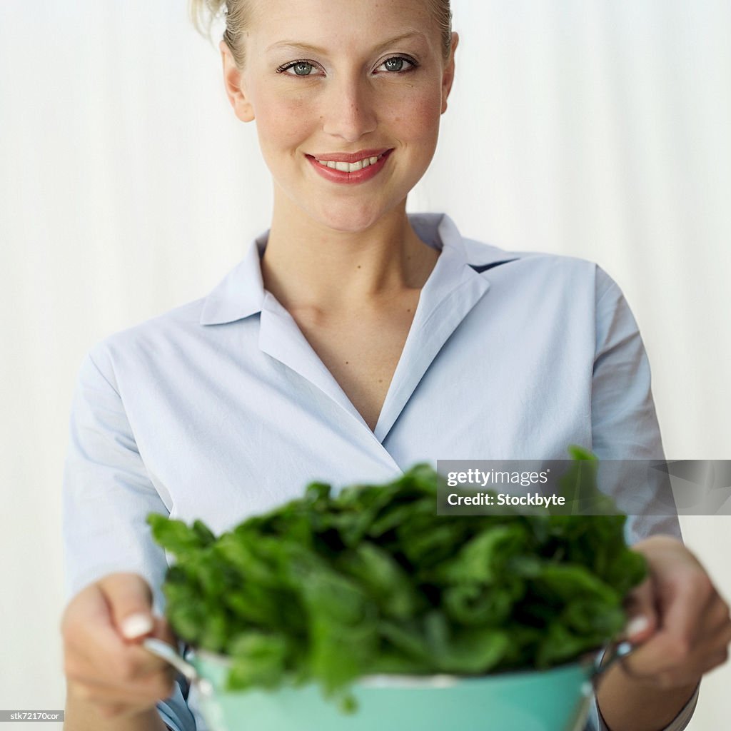 Portrait of a woman holding a colander of washed greens (selective focus)
