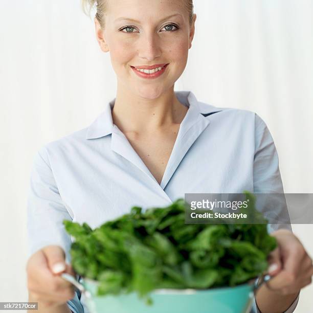 portrait of a woman holding a colander of washed greens (selective focus) - crucifers stock pictures, royalty-free photos & images