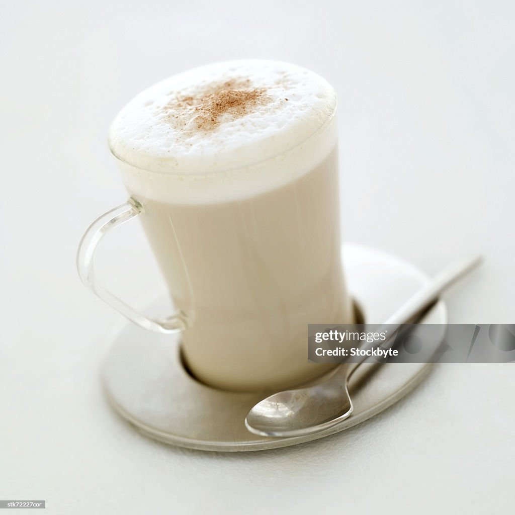 Close-up of a glass cup of cappuccino placed on steel saucer