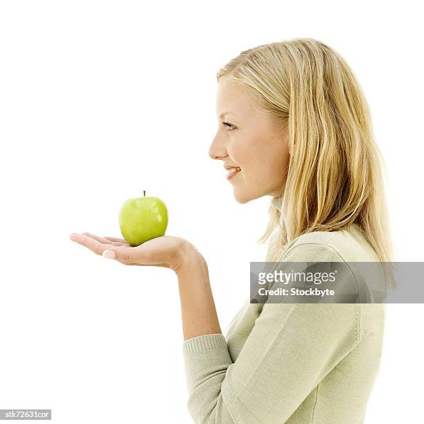 side profile of woman holding a fresh green apple in her palm - in profile stock pictures, royalty-free photos & images