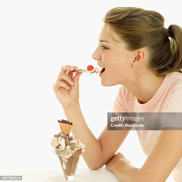 woman eating a wafer with ice-cream and a cherry - gefrorene süßspeise stock-fotos und bilder