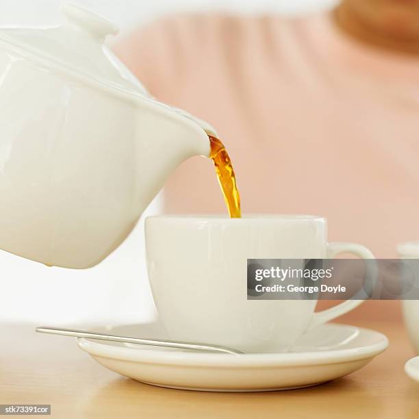 person pouring tea from a teapot into a cup - pitorro fotografías e imágenes de stock