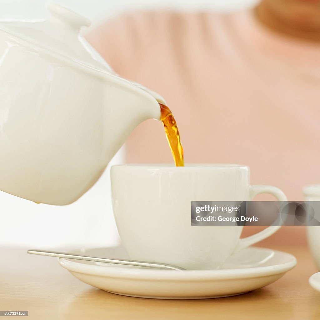Person pouring tea from a teapot into a cup