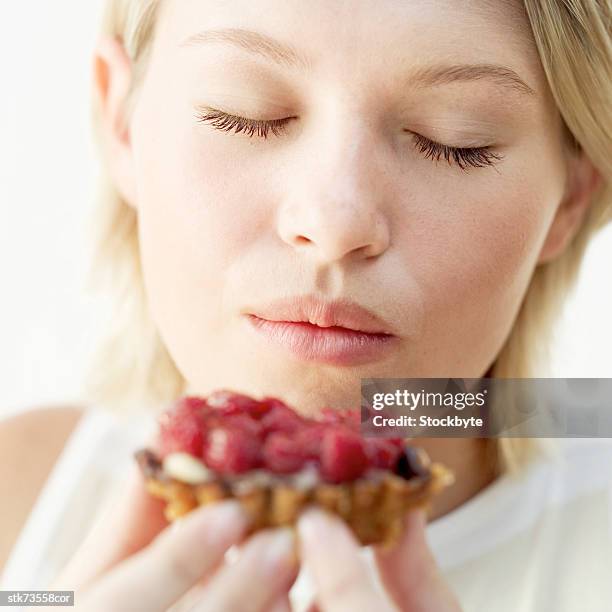 close-up of a woman holding a raspberry tart with her eyes closed - tony curtis in person at the film forum to present screenings of sweet smell stockfoto's en -beelden