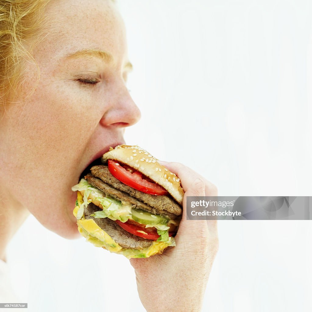 Side profile of a woman eating a hamburger