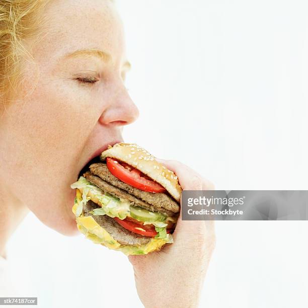 side profile of a woman eating a hamburger - in profile stock pictures, royalty-free photos & images