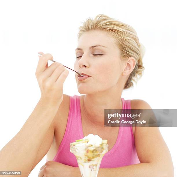 portrait of a woman eating an ice cream sundae with her eyes closed - gefrorene süßspeise stock-fotos und bilder