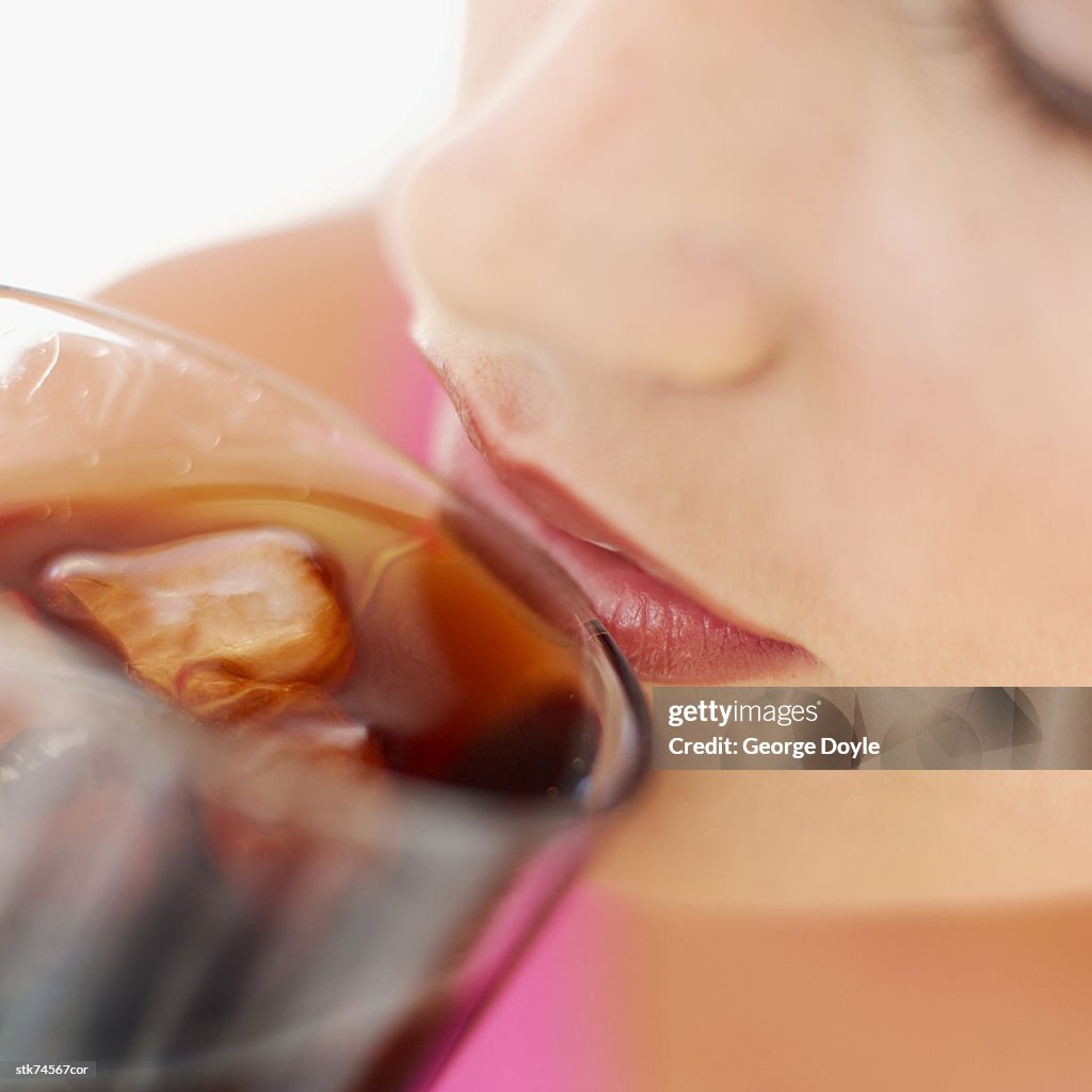 Close-up of a woman drinking cola from a glass