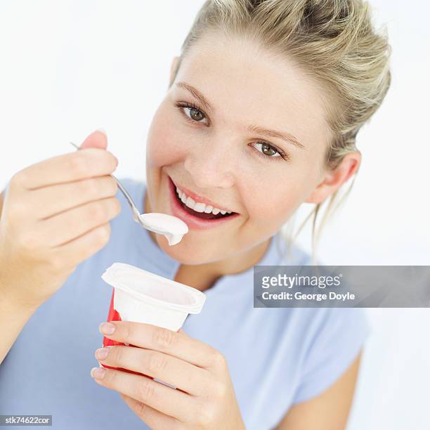 woman eating a yoghurt - yoghurt pot stock-fotos und bilder