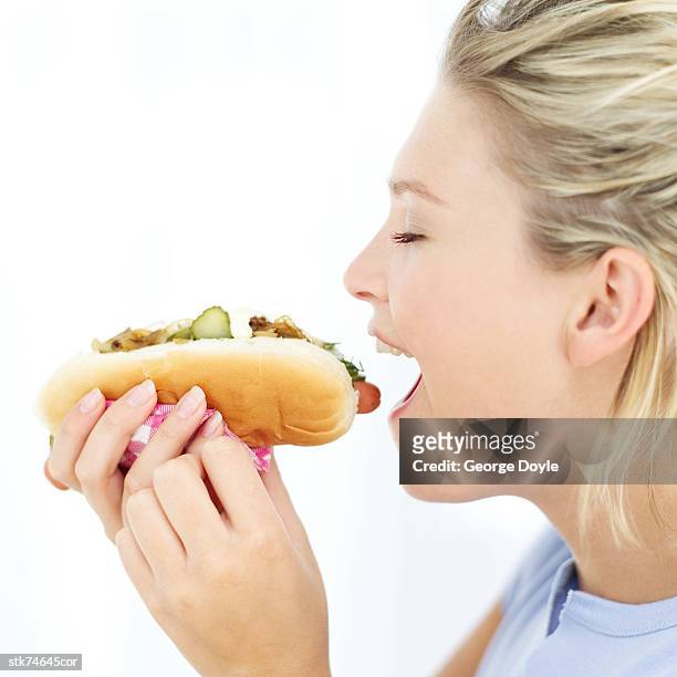 side profile of a woman eating a hotdog - in profile stock pictures, royalty-free photos & images