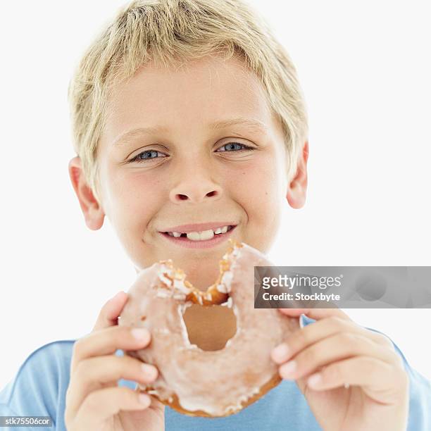 portrait of a boy (8-9) holding a sugar glazed doughnut - blue donut white background stock pictures, royalty-free photos & images