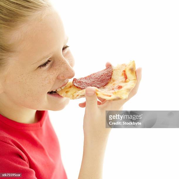 side profile of a young girl eating a slice of pepperoni pizza - in profile stock pictures, royalty-free photos & images