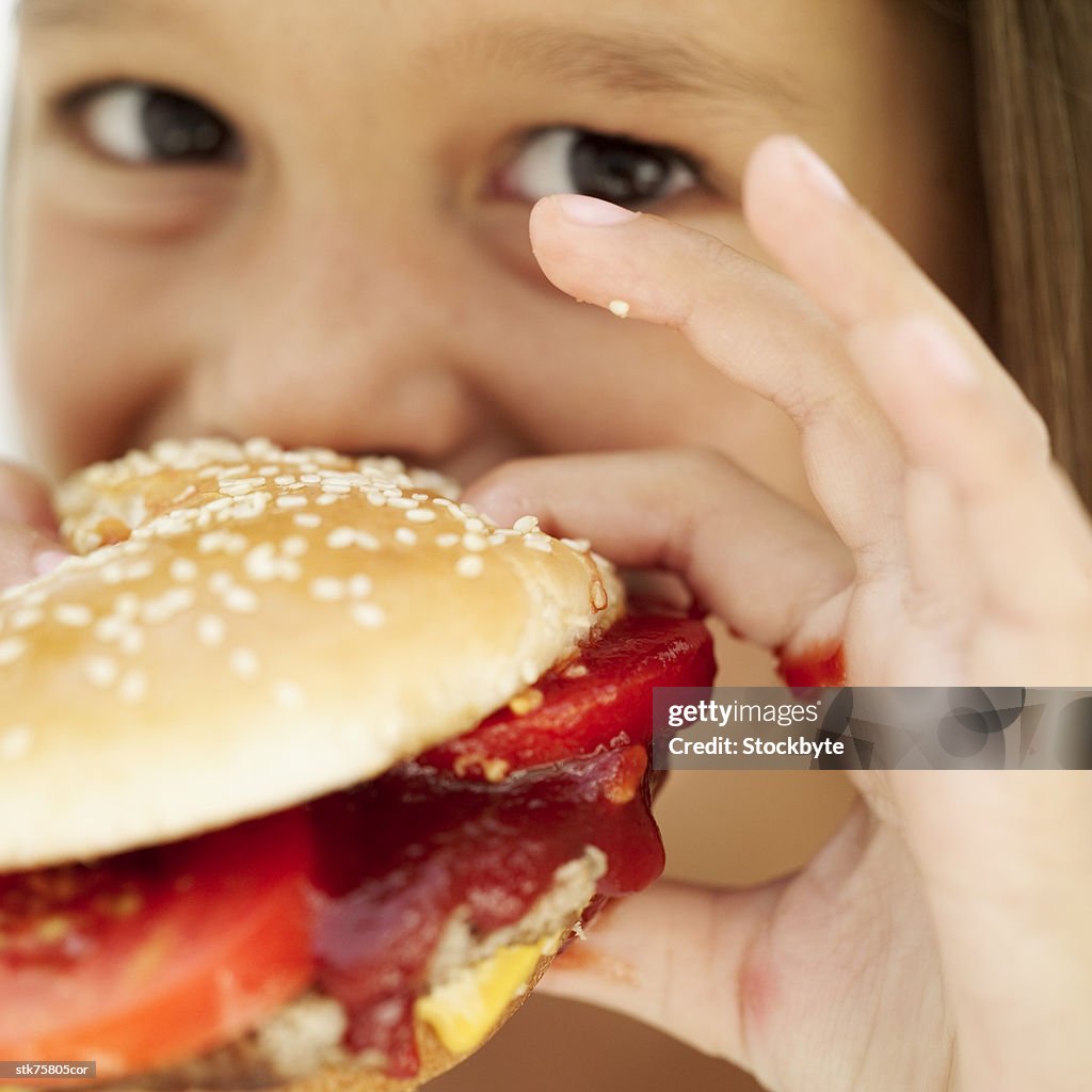 Close-up of a girl (6-7) eating a hamburger