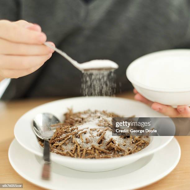 close-up of a man's hand sprinkling sugar on a bowl of cereal - sugar bowl crockery stock pictures, royalty-free photos & images