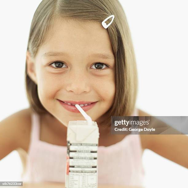 portrait of a girl (6-7) drinking a fruit drink with a straw - ジュースパック ストックフォトと画像