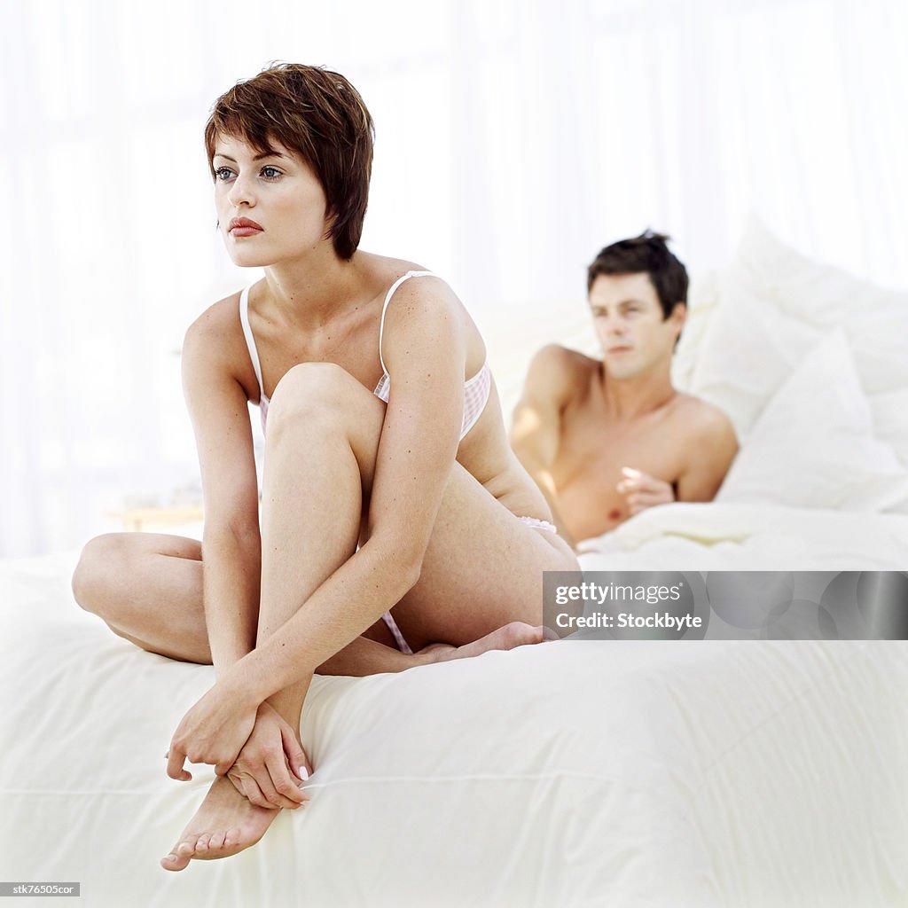Portrait of a young couple sitting apart on a bed