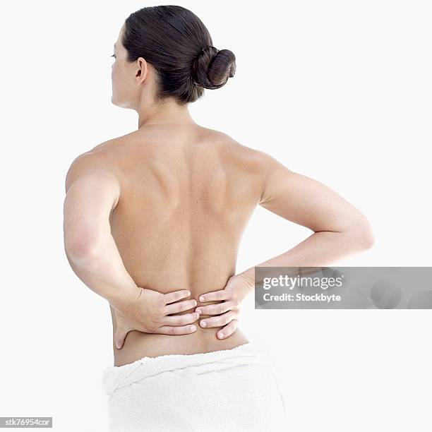 rear view of a nude woman holding her lower back - dos humain photos et images de collection