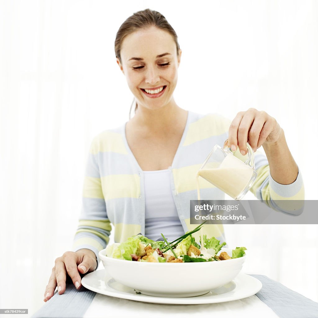 Portrait of a young woman dressing a salad