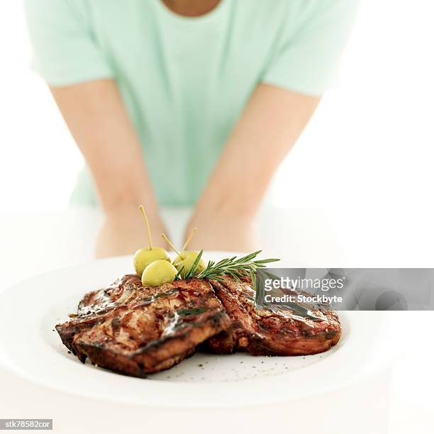 close-up of a woman's arms holding out a plate of roast meat - get out stock pictures, royalty-free photos & images