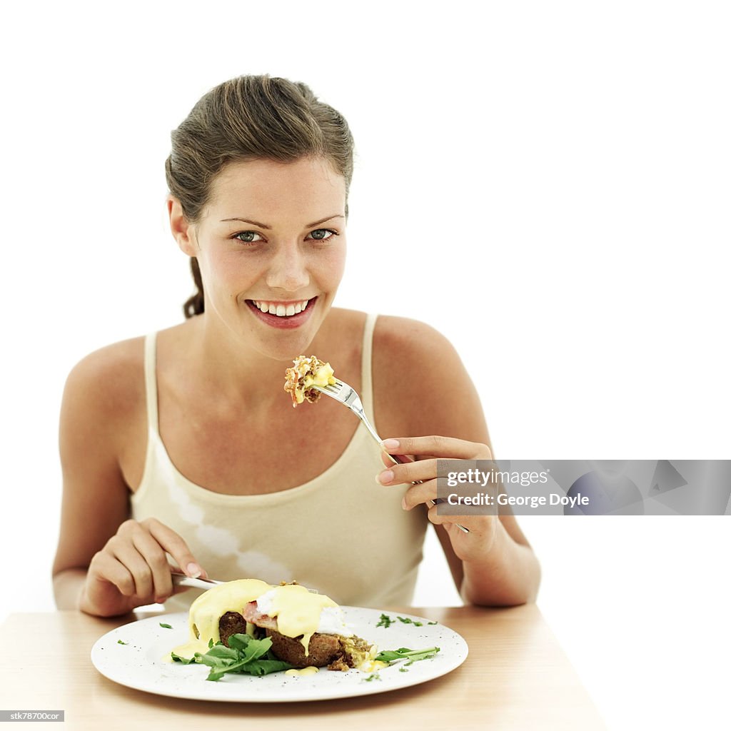 Portrait of a young woman eating a meal with a fork