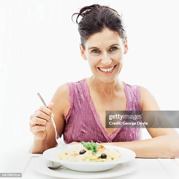 portrait of a woman holding a fork on a plate of pasta - alleen mid volwassen vrouwen stockfoto's en -beelden