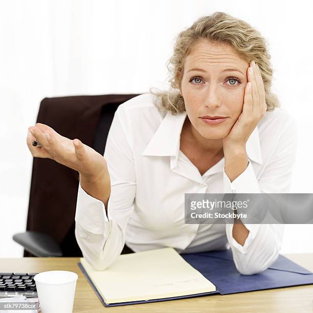 portrait of a young businesswoman sitting baffled at her desk - alleen mid volwassen vrouwen stockfoto's en -beelden