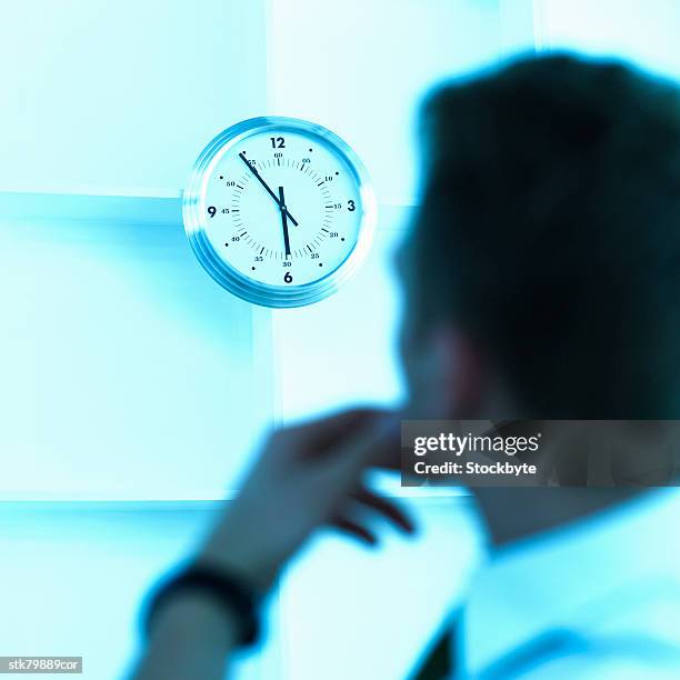 portrait of a young businessman looking at the wall clock - film tungstène photos et images de collection