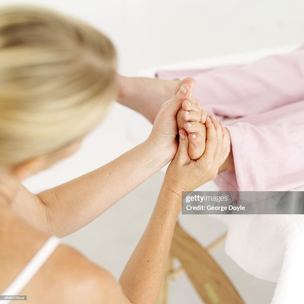High angle view of a masseuse massaging a persons foot
