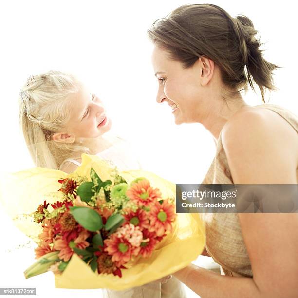 portrait of a young girl giving her mother a bouquet of flowers - open roads world premiere of mothers day arrivals stockfoto's en -beelden