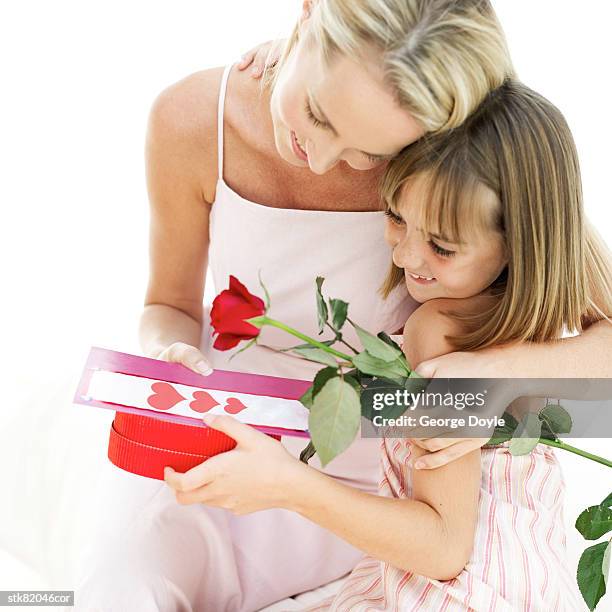 portrait of a mother hugging her daughter for a present and red rose - magnoliopsida bildbanksfoton och bilder