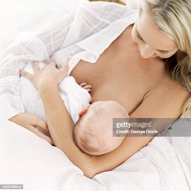 portrait of a young mother breastfeeding her baby - unknown gender stock pictures, royalty-free photos & images