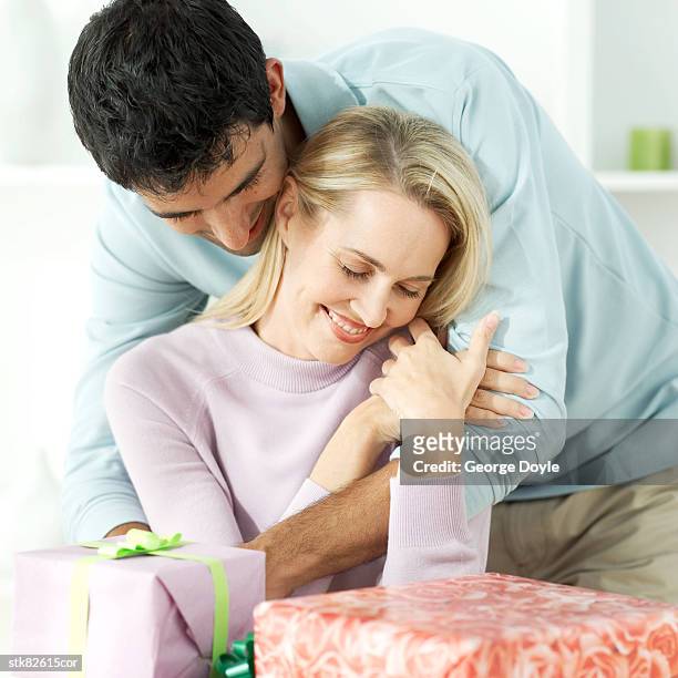 portrait of a young couple holding each other at a table piled with gifts - other stock-fotos und bilder