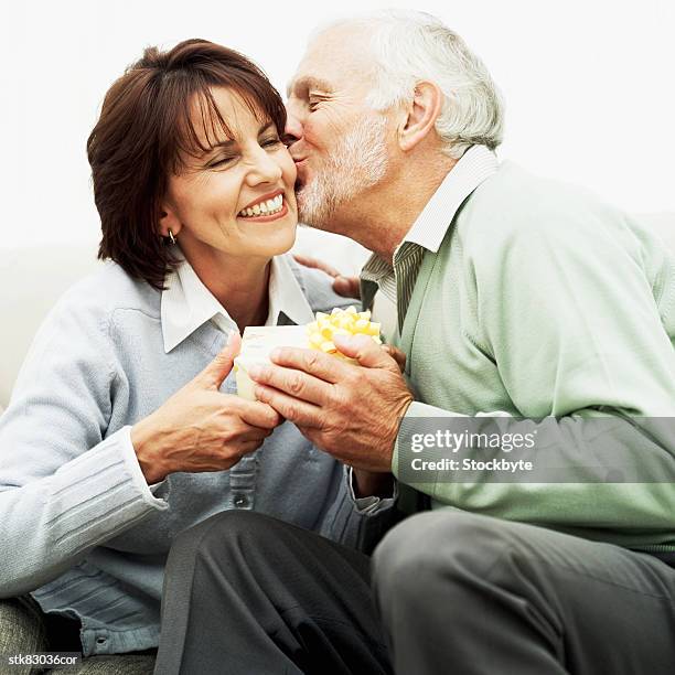 close-up of a senior man giving his wife a gift and a kiss on the cheek - house and senate dems outline constitutional case for trump to obtain congressional consent before accepting foreign payments or gifts stock pictures, royalty-free photos & images