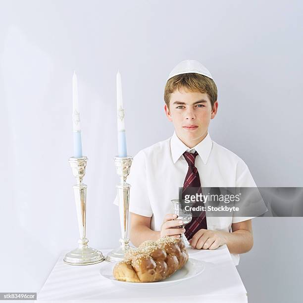 portrait of jewish boy (11-13) with a challah loaf and a kiddush cup - kiddush cup stock-fotos und bilder