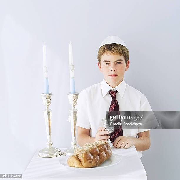 portrait of jewish boy (11-13) with a challah loaf and a kiddush cup - gorra a modo de casquete fotografías e imágenes de stock
