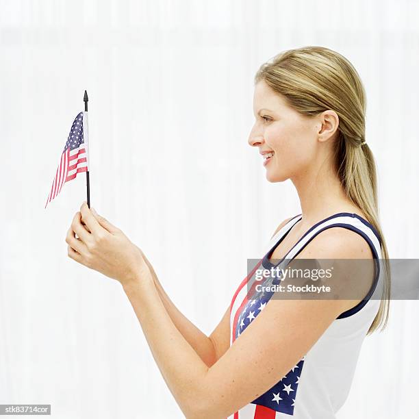 side view of a woman holding a miniature american flag - side by side photos et images de collection