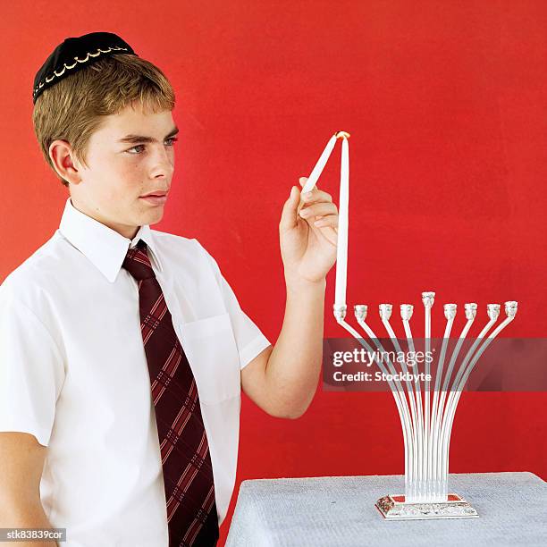jewish boy (11-13) lighting a candle on a menorah - gorra a modo de casquete fotografías e imágenes de stock