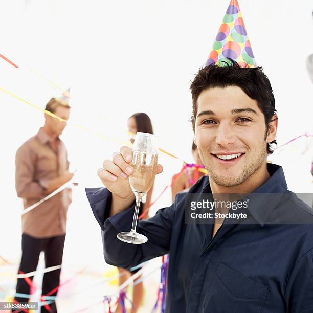 close-up of a man wearing a party cap holding up a champagne glass - wearing stock-fotos und bilder