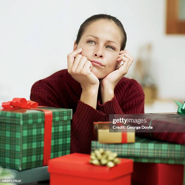 woman thinking beside a pile of christmas presents - house and senate dems outline constitutional case for trump to obtain congressional consent before accepting foreign payments or gifts fotografías e imágenes de stock