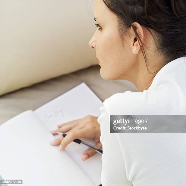 young woman lying down and writing in a book - writing instrument stock pictures, royalty-free photos & images