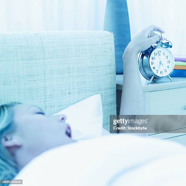 woman waking up and turning off an alarm clock - olivia wilde co hosts event at birchbox soho in celebration of conscious commerce birchbox collaboration stockfoto's en -beelden