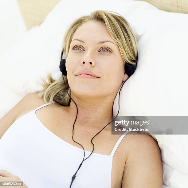 elevated view of a woman lying in bed listening to music - recreational equipment stock pictures, royalty-free photos & images