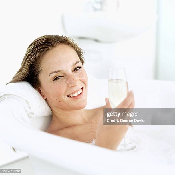 woman lying in a bubble bath and holding a glass of champagne - beautiful woman bath stock-fotos und bilder